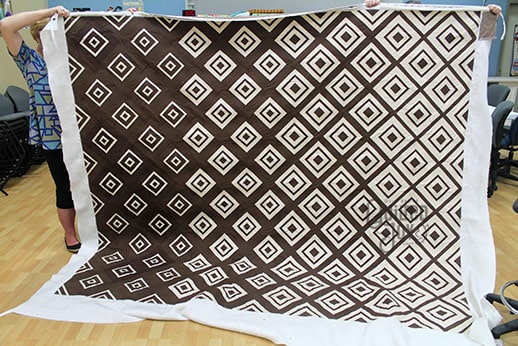 Carol shows off her brown and cream quilt after renting a longarm machine at Quilted Joy